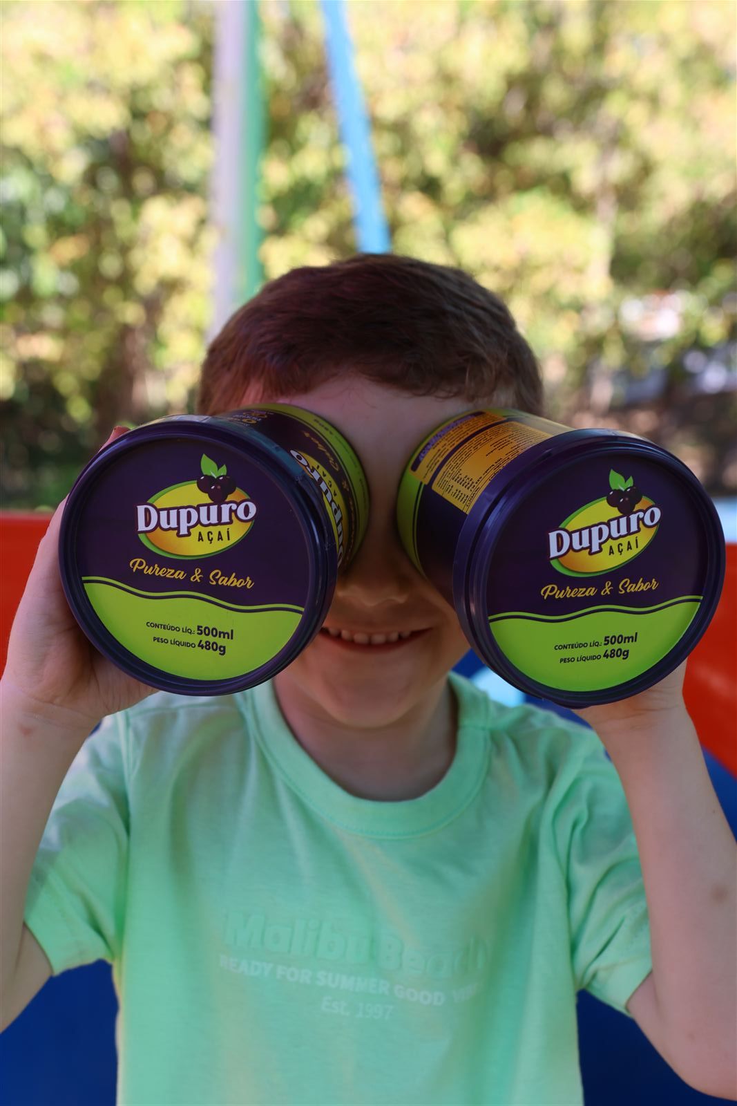 Criança brincando com potes de açaí Dupuro como binóculos