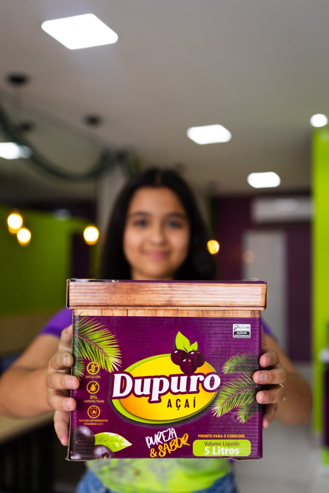 Menina segurando uma caixa de 5 litros de açaí Dupuro